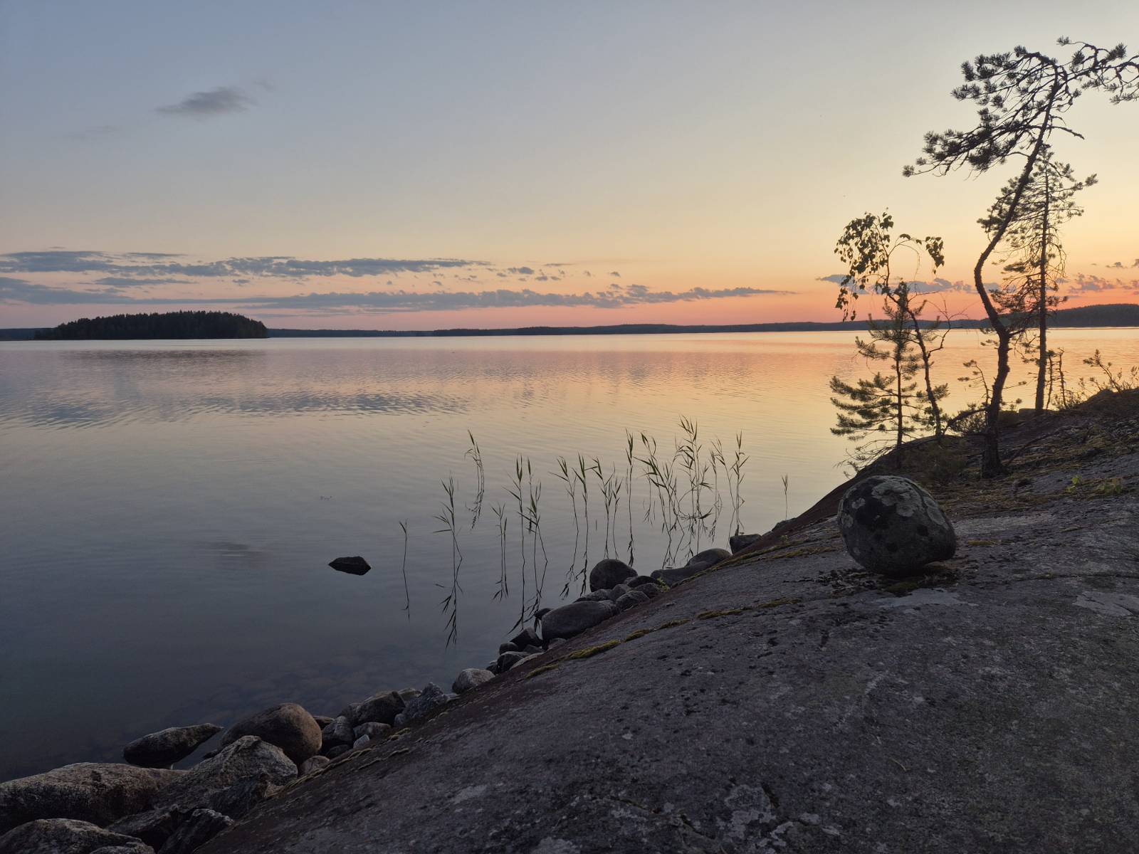 Rauhallinen järvimaisema auringonlaskussa kalliolta kuvattuna